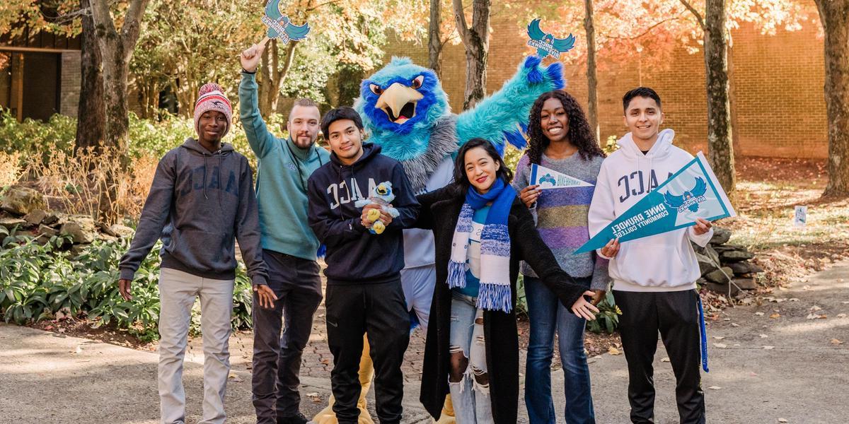 Students laughing and posing with AACC mascot, Swoop.